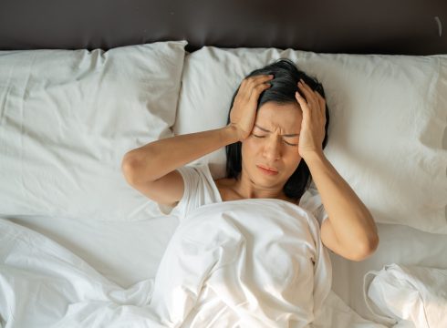Unhappy exhausted mature woman with closed eyes lying in bed, touching temples close up, tired female suffering from headache or migraine, feeling unwell, suffering from insomnia, lack of sleep